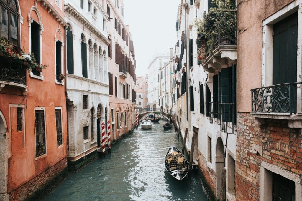 Venice Venice canal with gondolas and boats passing between colourful old buildings and a small arched bridge