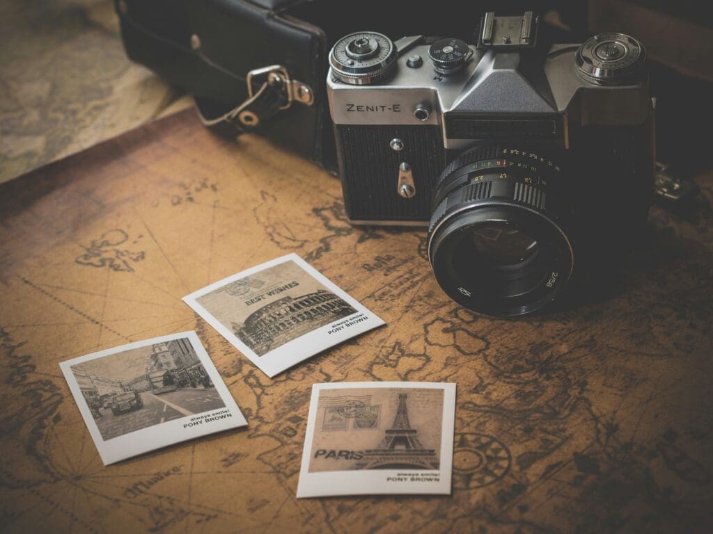 Vintage Zenit-E film camera on an old map with retro travel postcards of Paris, Rome, and London