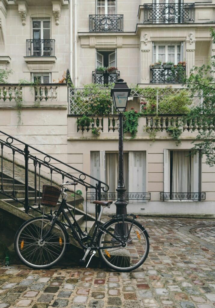 Photo by John Towner on Unsplash Vintage bicycle with basket leaning against a lamppost on a cobbled Parisian street with classic apartments and balconies in the background