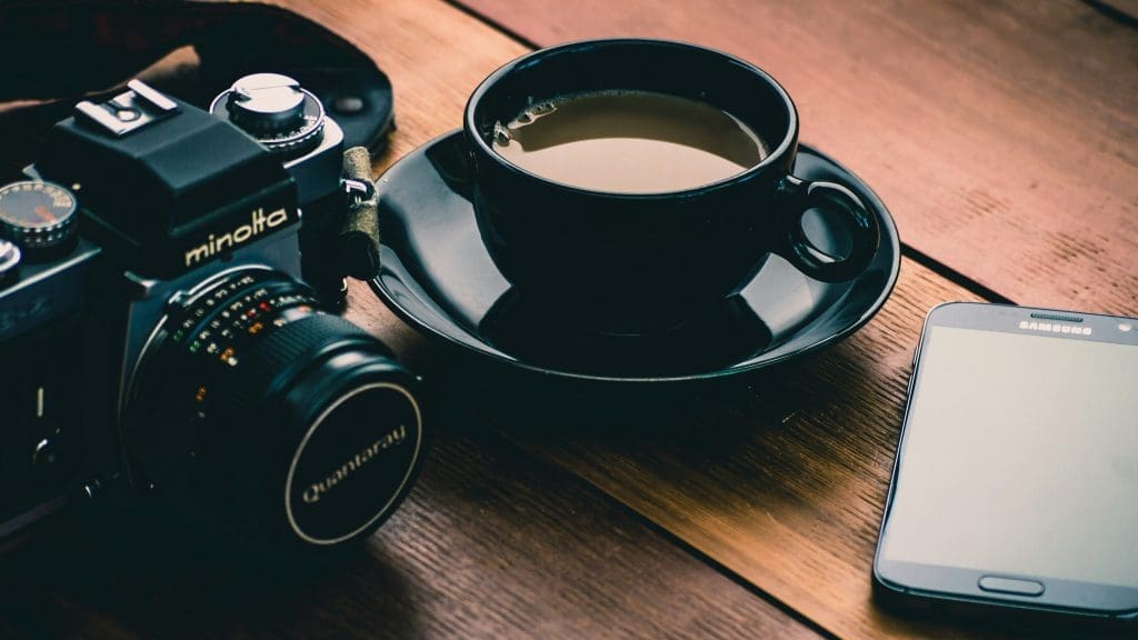 Photo by Stephen Cook on Unsplash Vintage Minolta camera beside black coffee cup and Samsung smartphone on wooden table