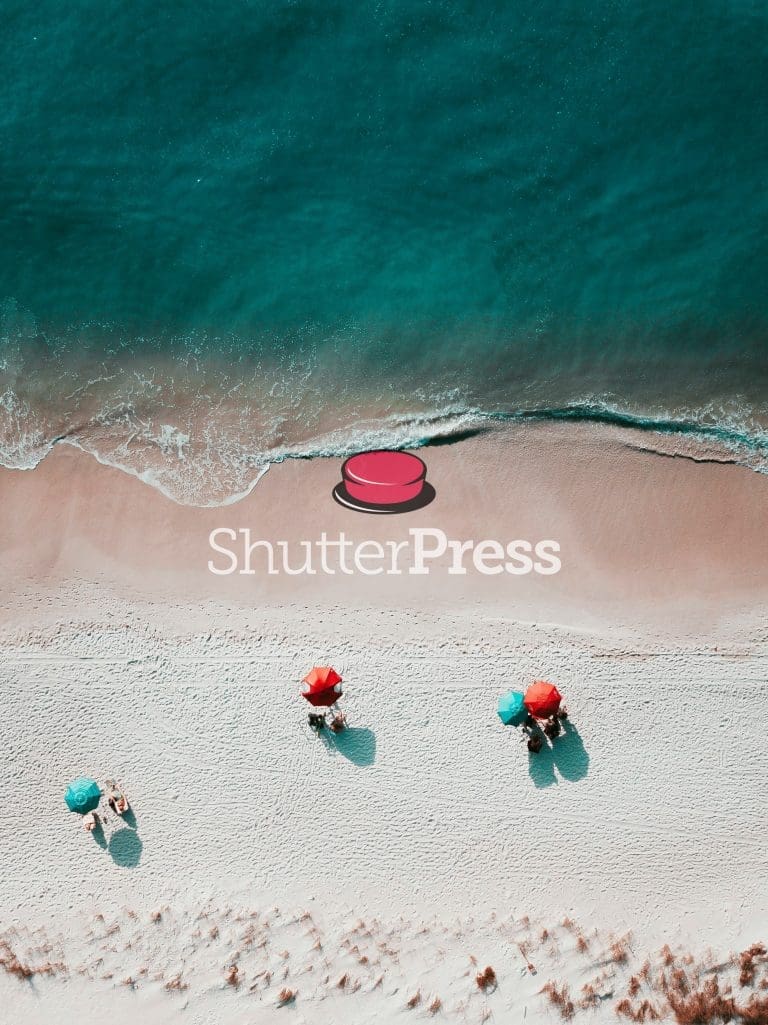 Aerial view of turquoise sea and sandy beach with red umbrellas and ShutterPress logo watermark