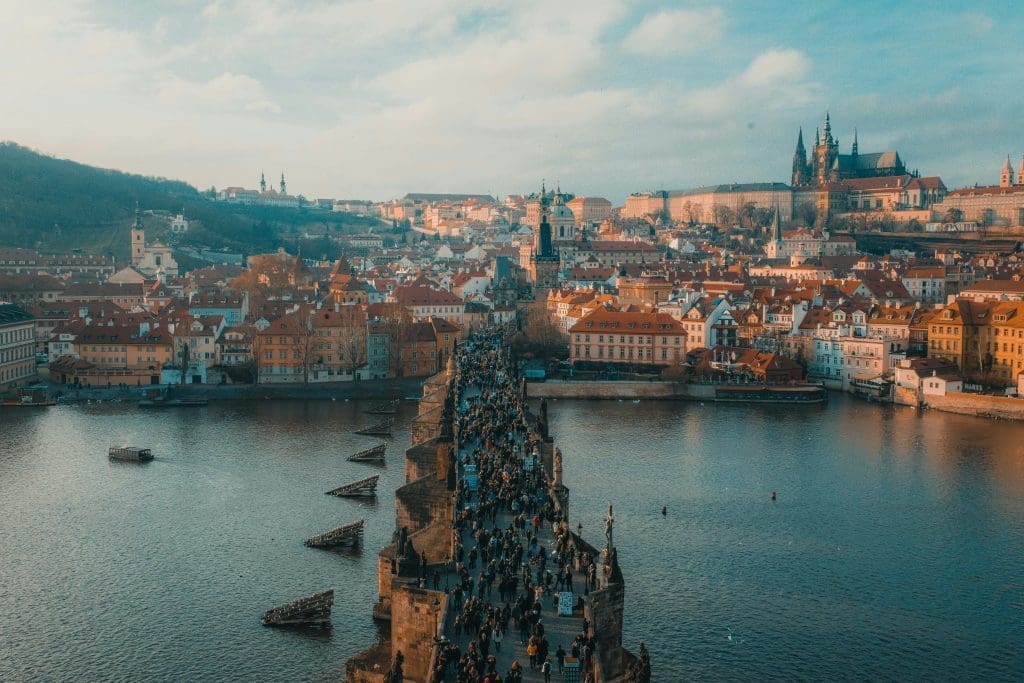 Photo by anthony delanoix on unsplash Aerial view of Charles Bridge crowded with people, with Prague Castle and old town skyline in the background, Czech Republic