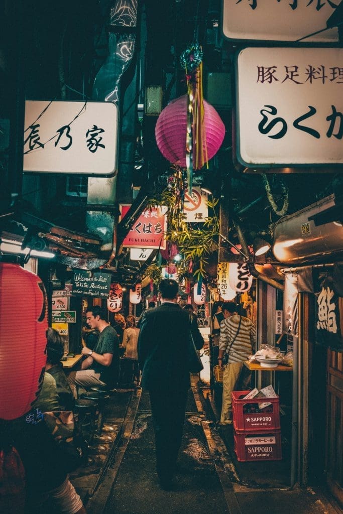 Crowded narrow alley with lanterns and neon signs at night in Shinjuku Tokyo Japan