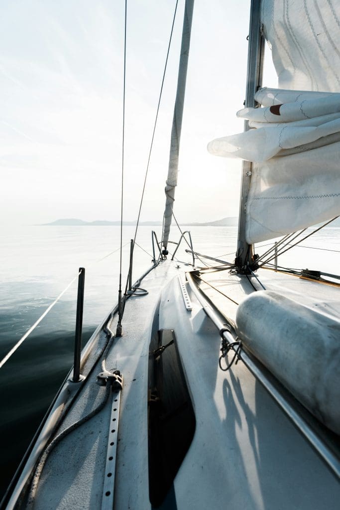 Photo by daniel olah on unsplash View from the deck of a sailing boat on calm water with sails partially raised at sunset