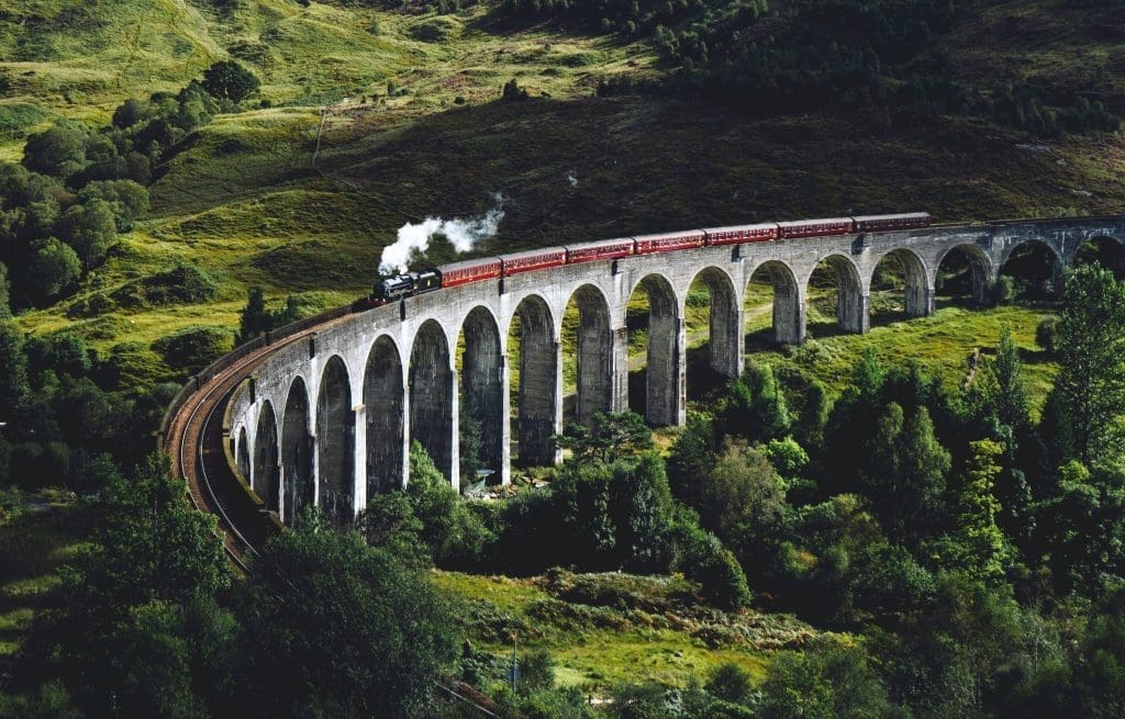 Photo by jack anstey on unsplash Steam train crossing the Glenfinnan Viaduct in the Scottish Highlands, surrounded by green hills