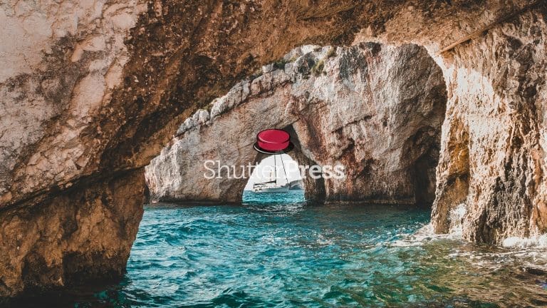 Sailing boat framed by natural rock arch over turquoise sea in Zakynthos Greece, ShutterPress watermark
