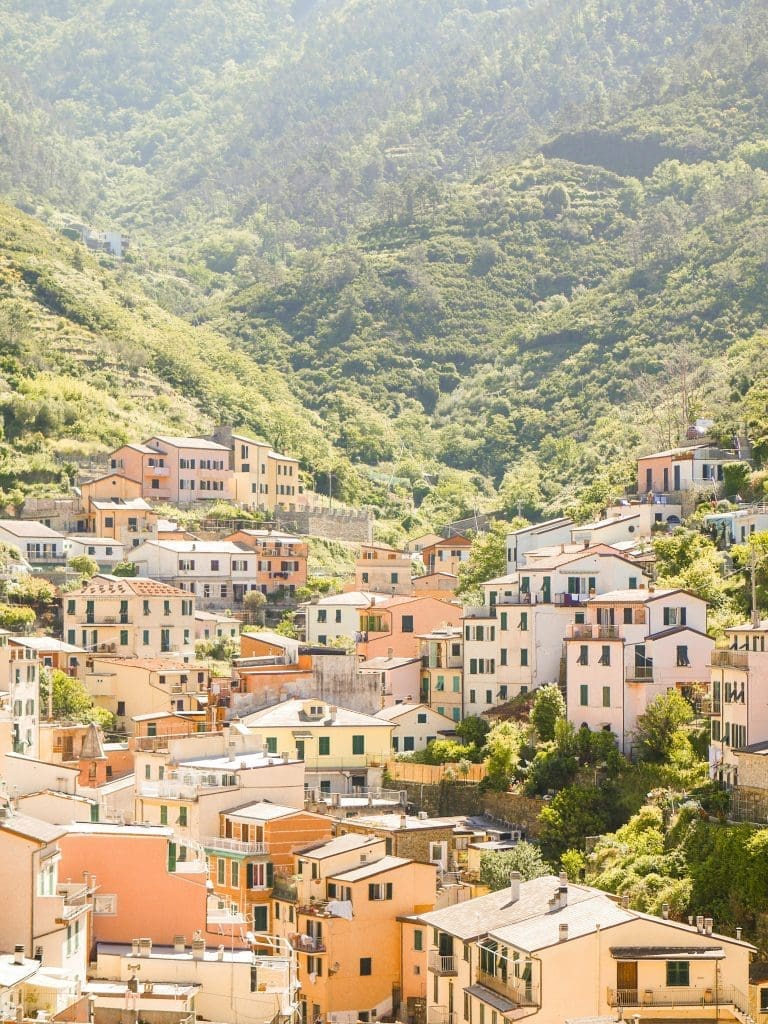 Photo by sarah elizabeth on unsplash Colourful hillside village in Cinque Terre with pastel houses and green mountains in the background