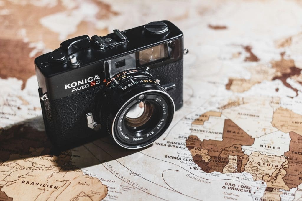 Vintage Konica Auto S3 film camera placed on a world map with Africa and Europe in focus, symbolising travel and photography