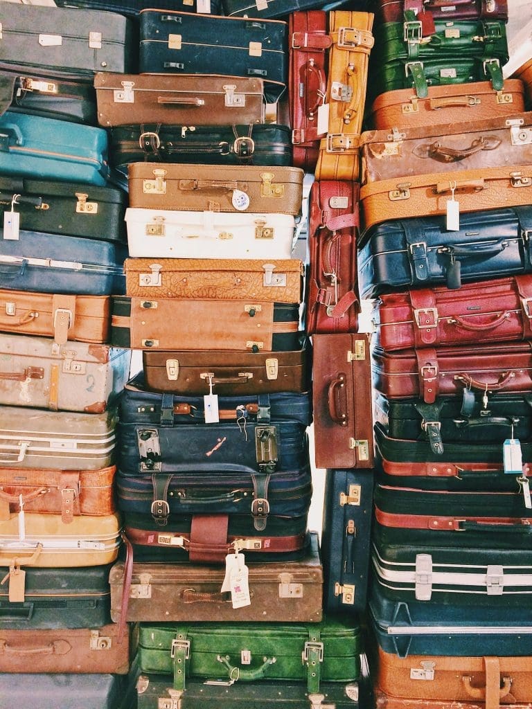 Photo by Caroline Selfors on Unsplash stack of vintage suitcases in varied colours and textures for travel concept