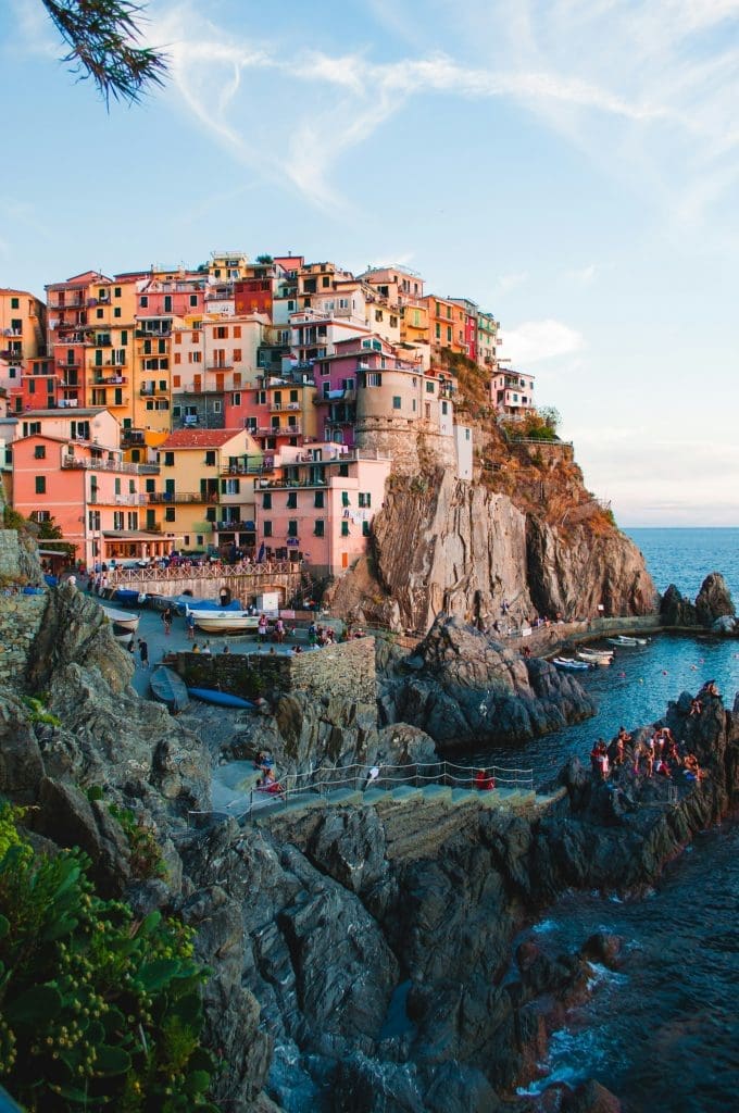 Photo by Jack Ward on Unsplash A vibrant cluster of pastel-coloured houses perched on steep cliffs overlooking a shimmering sea under a pale sky.