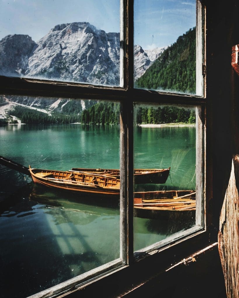 Photo by Luca Bravo on Unsplash Two wooden boats floating on emerald lake with snow-capped mountains at Lago di Braies Italy