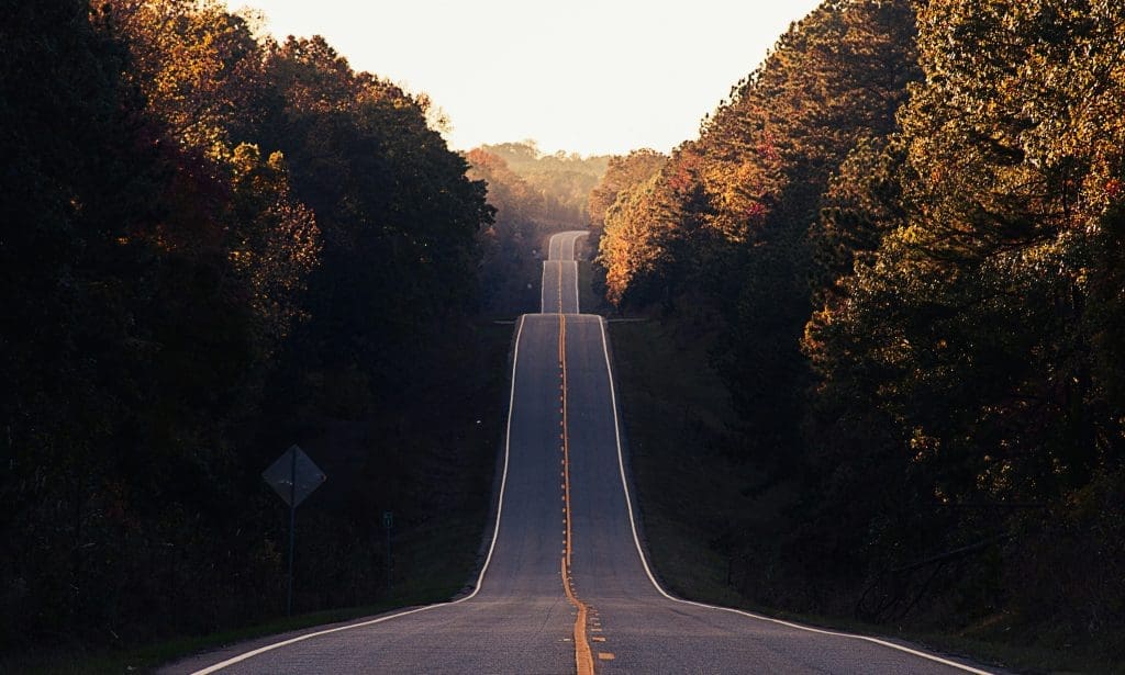 Photo by Matt Foxx on Unsplash Long winding road through autumn forest at sunset with golden light on trees